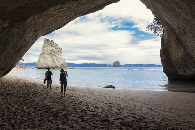 Couple taking pictures at scenic Cathedral Cove New Zealand