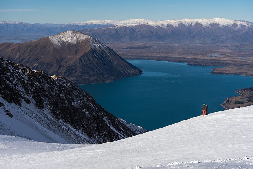 Woman snowboarder enjoys the majestic view of Ohau Snow Fields in New Zealand
