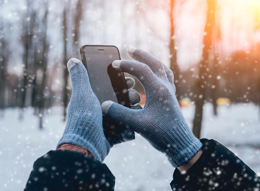 Man using smartphone in winter with gloves for touch screens. Backgound