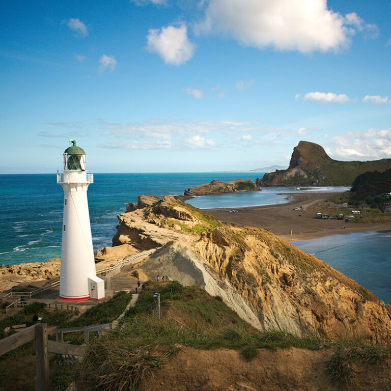 A lighthouse overlooking a beach and bay area in New Zealand