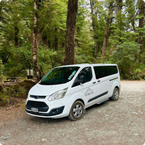 A van of The Road Trip New Zealand parked in front of some trees