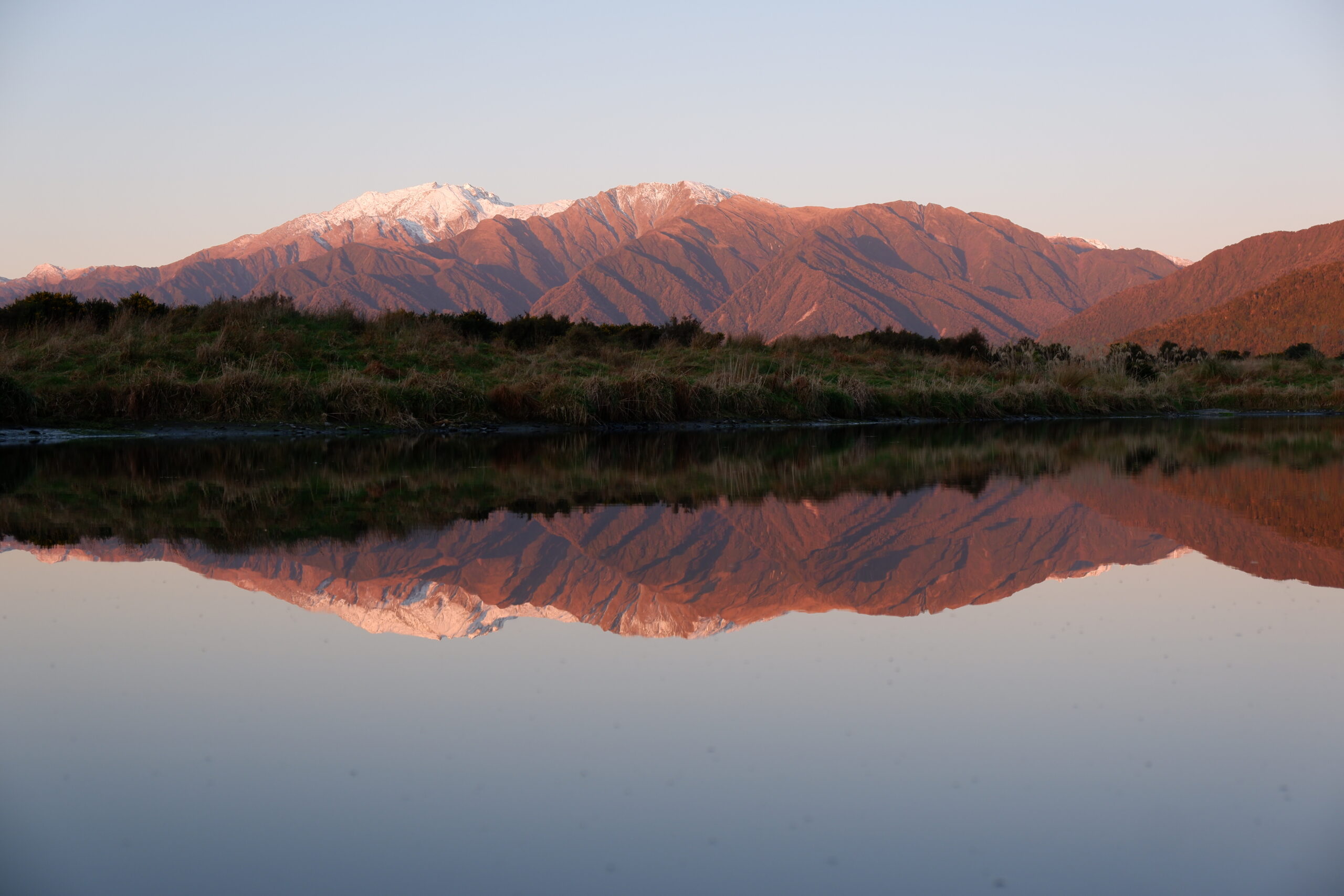 A mountain with snow reflected on a lake in the west coast of New Zealand