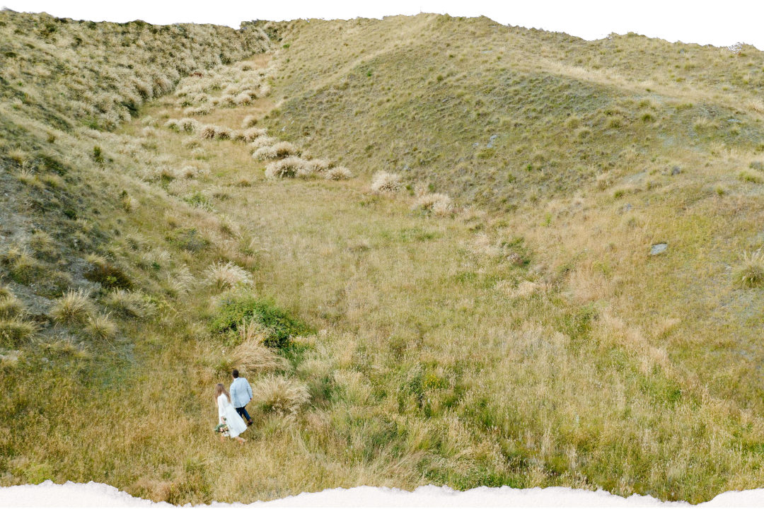 Two people walking together through an alpine meadow in Otago