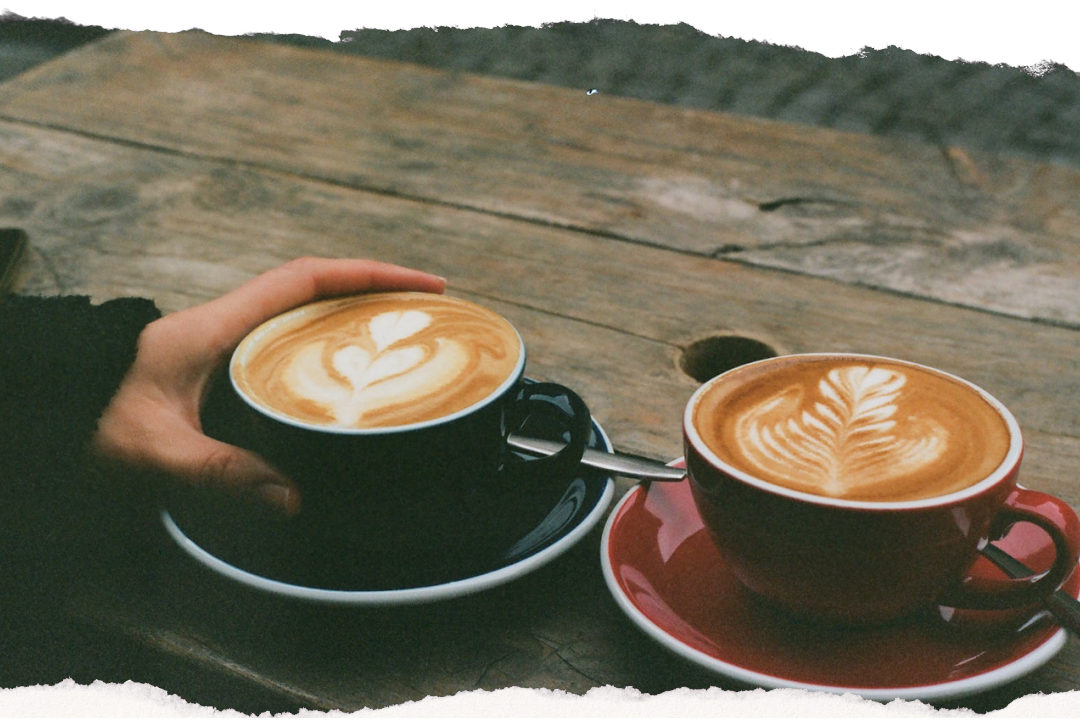 Two flat white coffees with latte art on a rustic wooden table