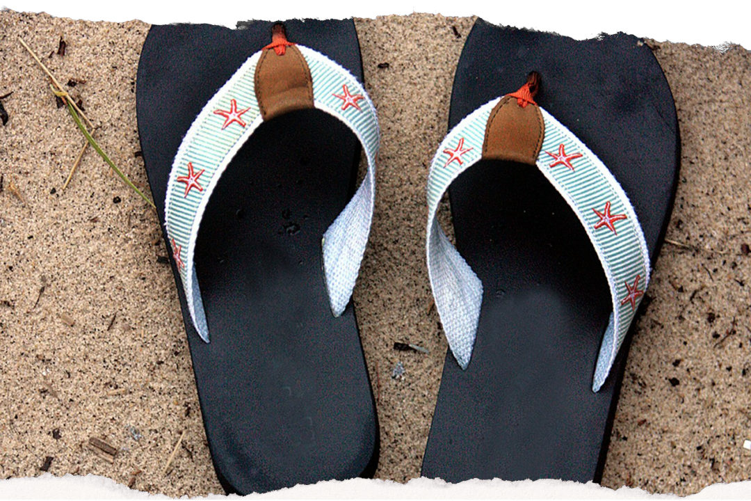 Jandals (flip-flops) resting on sandy beach