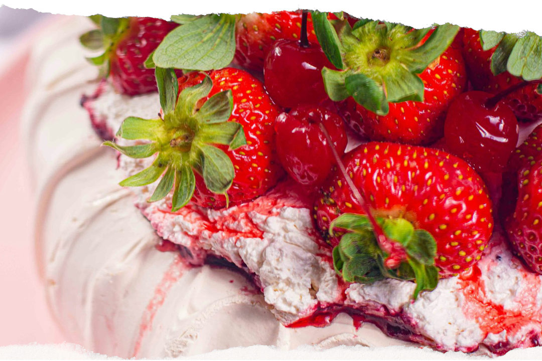 Pavlova dessert topped with whipped cream and fresh strawberries