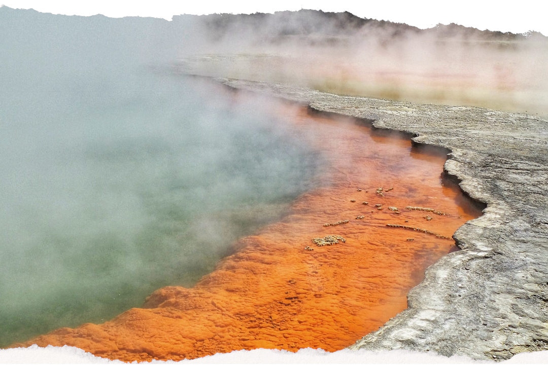 Vivid orange and turquoise geothermal pool with rising steam at Wai-O-Tapu, Rotorua