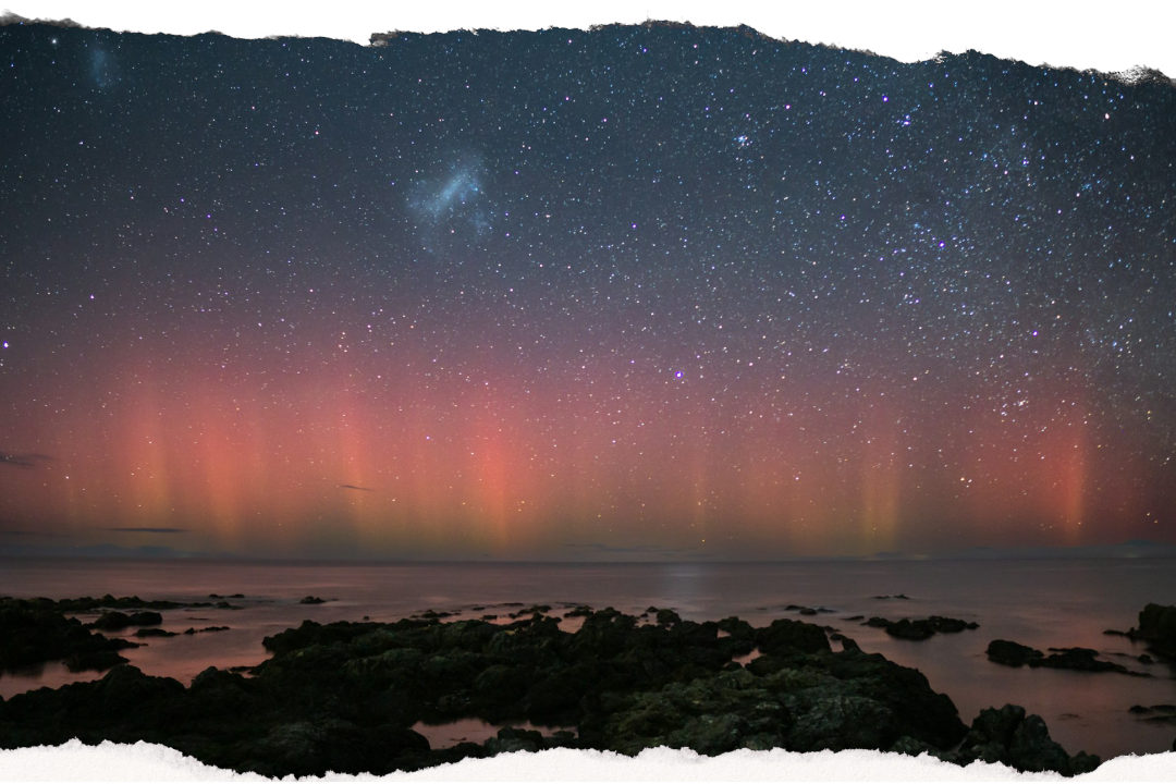 Aurora australis glowing pink and green over the New Zealand coast